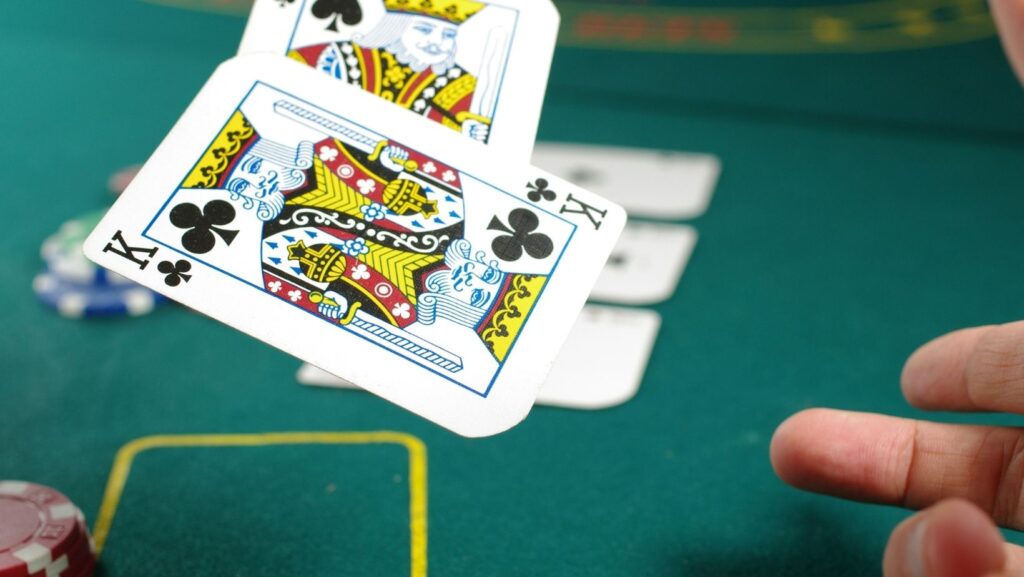 Hands dealing cards on a green felt poker table at night, representing the traditional game that has since migrated to mobile screens